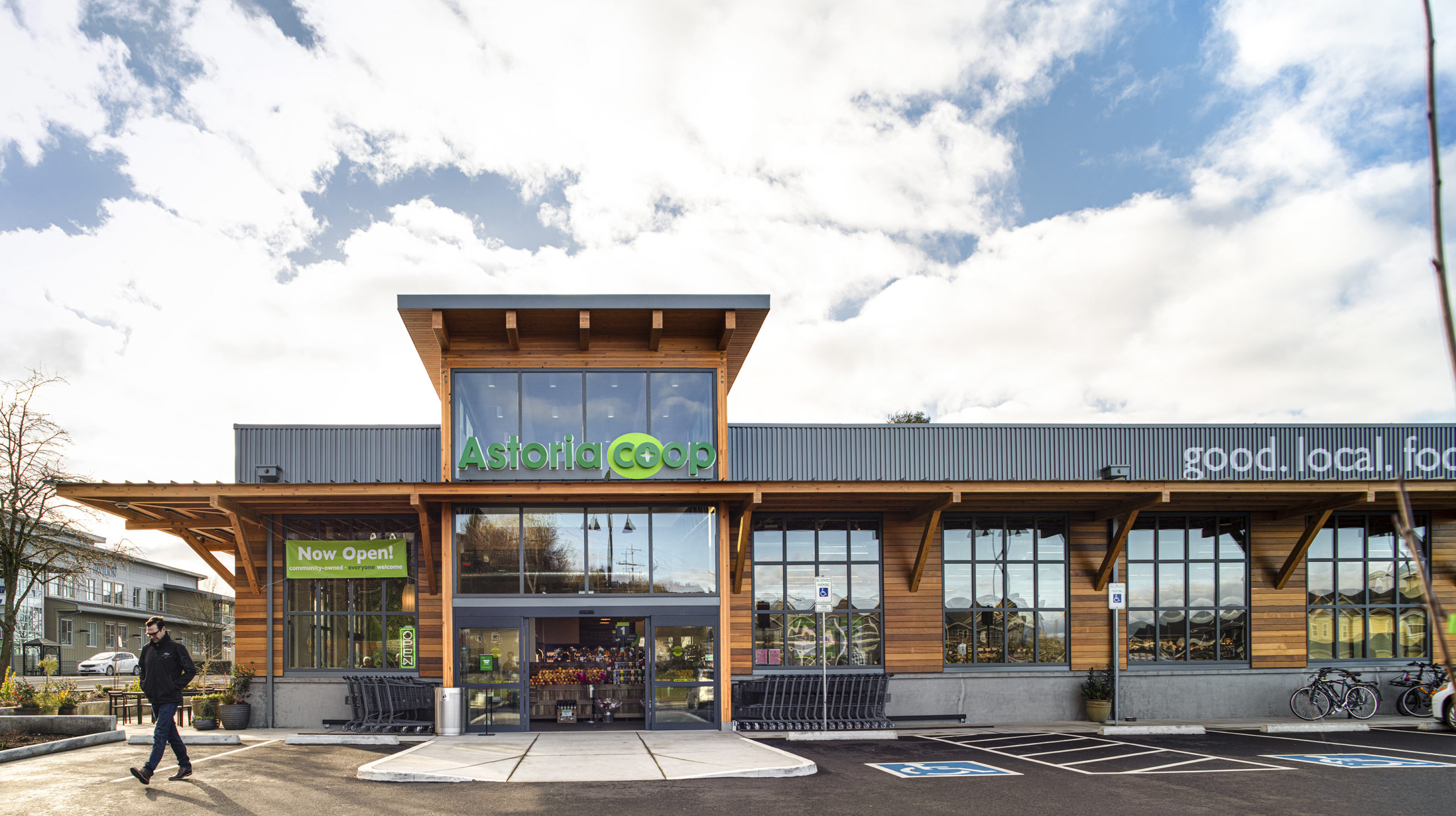 exterior overall view of Astoria Co Op building with customer walking out